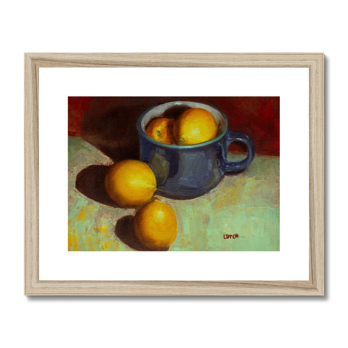 Painting of lemons sitting in and beside a blue teacup. Framed with a light oak frame and white mount. 