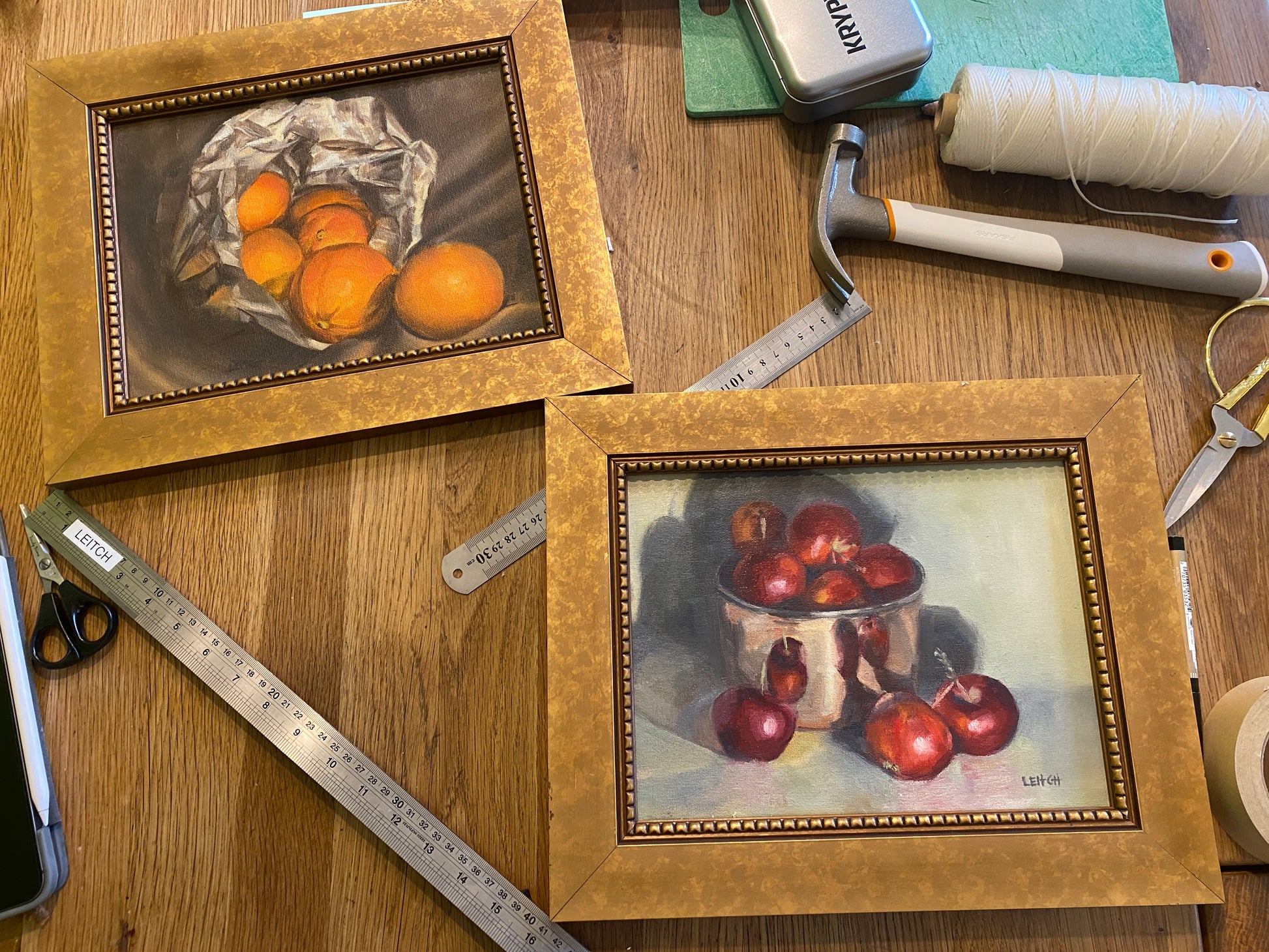 two oil paintings with gold frames, surrounding by framing detritus